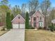 Charming brick two-story home with a two-car garage, landscaping, and mature trees at 3887 Hickory Manor Dr, Suwanee, GA 30024