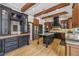 Elegant kitchen featuring a black central island, wooden cabinetry, stainless steel appliances, and wooden beam ceilings at 3887 Hickory Manor Dr, Suwanee, GA 30024