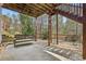 Covered patio with wooden swing, stone base, and access to a brick-paved patio and lush backyard at 3887 Hickory Manor Dr, Suwanee, GA 30024