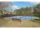 Community tennis courts with nets and benches, surrounded by mature trees and fencing, provide a private recreational area at 3887 Hickory Manor Dr, Suwanee, GA 30024