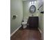 Cozy half bathroom featuring an oval mirror, wood-look floors, and a dark vanity at 1535 Wilkes Crest Dr, Dacula, GA 30019