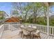Outdoor deck with a wooden table and white chairs surrounded by lush greenery and a view of neighboring houses at 791 Woodland Se Ave, Atlanta, GA 30316