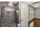 Bathroom featuring a tiled walk-in shower, open doorway, and hardwood floors in the adjacent room at 791 Woodland Se Ave, Atlanta, GA 30316