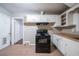Kitchen with linoleum tile floor and white cabinets surrounding a black range, with a door leading to the rest of the home at 1753 Thomas Ter, Decatur, GA 30032
