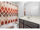 A simple bathroom with a patterned shower curtain, dark cabinets, and tile floor at 312 Amble Side, Mcdonough, GA 30252