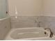 Close up of a bright, white bathtub with marble tile surround and gold fixtures at 407 Johnson Ct, Alpharetta, GA 30009
