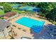 Aerial view of the community pool featuring tables, chairs and umbrellas with tennis courts in the background at 7940 Royal Melbourne Way, Duluth, GA 30097