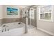 Bathroom featuring a corner soaking tub with tile surround and a glass-enclosed shower at 207 Magnolia Creek Way, Woodstock, GA 30188