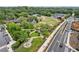 Wide aerial view of a community park with a central fountain, gazebo, stage, and a mix of green spaces and roads at 207 Magnolia Creek Way, Woodstock, GA 30188