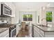 Close-up of the kitchen with granite countertops, stainless steel appliances, and a view to the outside at 207 Magnolia Creek Way, Woodstock, GA 30188