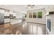 Open-concept living room with hardwood floors, fireplace, and a modern kitchen with stainless steel appliances at 207 Magnolia Creek Way, Woodstock, GA 30188