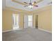 Spacious bedroom featuring a tray ceiling, ceiling fan, walk-in closet and neutral carpet at 453 Clematis Ct, Temple, GA 30179