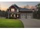 Charming two-story home featuring a manicured lawn, brick accents, and a two-car garage at sunset at 453 Clematis Ct, Temple, GA 30179