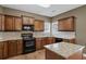 Well-equipped kitchen featuring dark wood cabinets, granite countertops, and stainless steel appliances, with an island and pendant lighting at 453 Clematis Ct, Temple, GA 30179