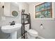 Powder room with pedestal sink, decorative mirror, and natural light at 6695 Woodstock Rd, Acworth, GA 30102