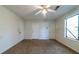 Bedroom featuring three closets, a ceiling fan, neutral carpet and large window at 5255 Biffle Downs Rd, Stone Mountain, GA 30088