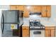 Compact kitchen features a stainless steel range, black refrigerator, and oak cabinetry at 870 Chapman Cir, Stone Mountain, GA 30088