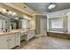 Bathroom featuring double vanity, white cabinets, and soaking tub with tile surround at 2505 Weber Heights Way, Buford, GA 30519