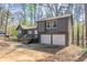 View of home's exterior with two-car garage and wooded setting at 477 Victoria Rd, Woodstock, GA 30189