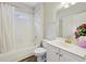 Bright bathroom featuring a white tub/shower combo, white vanity, and gold fixtures at 1780 Riverglen Dr, Suwanee, GA 30024