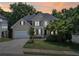 Charming two-story traditional home with tan siding, an attached garage and a well-manicured lawn at dusk at 1780 Riverglen Dr, Suwanee, GA 30024