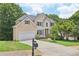 Charming two-story traditional home with tan siding, an attached garage, well-manicured lawn and a mailbox at 1780 Riverglen Dr, Suwanee, GA 30024
