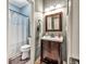 Half bathroom featuring a wooden vanity, toilet, decorative mirror and gray accent walls at 5848 Deer Crossing Dr, Sugar Hill, GA 30518