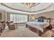 Spacious bedroom featuring tray ceilings, a ceiling fan, and a large window at 5848 Deer Crossing Dr, Sugar Hill, GA 30518