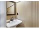 Bathroom with a pedestal sink, wood paneled walls, decorative mirror, and chrome fixtures at 3270 River Summit Trl, Duluth, GA 30097