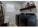 Bright laundry room with sleek, modern washer and dryer units, a built-in utility sink, and ample storage shelving at 211 Orchard Trl, Canton, GA 30115