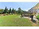 The backyard has a brick fire pit surrounded by green grass and shrubbery offering space for outdoor gatherings at 7130 Ansley Park Way, Cumming, GA 30028