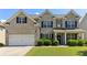 Charming brick two-story home featuring a manicured lawn, two car garage, and welcoming front porch at 7130 Ansley Park Way, Cumming, GA 30028
