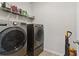 This laundry room includes a washer, dryer, wire rack shelving, and tile floors at 7130 Ansley Park Way, Cumming, GA 30028