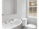 Clean and bright powder room featuring a sink, mirror, toilet, and a window with a view at 1162 Buice Lake Pkwy, Acworth, GA 30102