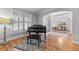 Elegant living room features a piano, hardwood floors, and an open archway to the dining room at 3520 Millwater Xing, Dacula, GA 30019