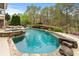 Backyard showcasing a stunning pool with an integrated spa, rock features, and lush landscaping at 3520 Millwater Xing, Dacula, GA 30019