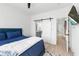 Bedroom with white walls, hardwood floors, a blue bed, a sliding barn door to a bathroom at 699 Pryor Sw St # 4, Atlanta, GA 30315