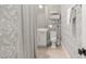 Full bathroom showcasing modern gray wallpaper, a white vanity, and shelving for towels behind a neutral-colored shower curtain at 803 Courtenay Ne Dr, Atlanta, GA 30306