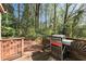 Outdoor deck area featuring a barbecue grill and views of a lush wooded backyard at 3186 Sugarplum Ne Rd, Atlanta, GA 30345