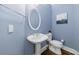 Powder room features a pedestal sink, oval mirror, updated light fixture, and blue painted walls at 460 Laurel Chase Ct, Atlanta, GA 30327