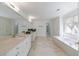 Bright main bathroom features double sinks, a vanity, a soaking tub, and neutral tile flooring at 460 Laurel Chase Ct, Atlanta, GA 30327