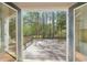 View from the doorway onto a wooden back deck surrounded by lush, green trees in a private backyard at 740 Trillium Ln, Lilburn, GA 30047