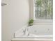 Soaking tub with jets offers a relaxing retreat with natural light from the window at 740 Trillium Ln, Lilburn, GA 30047