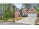 Charming two-story red brick home featuring a manicured lawn, two-car garage, and beautiful bay window at 740 Trillium Ln, Lilburn, GA 30047
