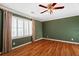 Bedroom with hardwood floors, light-trim windows with shutter and curtain coverings, and an overhead fan at 1909 Hickory Level Rd, Villa Rica, GA 30180