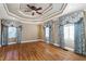 Bedroom with hardwood floors, decorative tray ceiling, ceiling fan, and windows with patterned curtains at 1909 Hickory Level Rd, Villa Rica, GA 30180