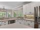 Kitchen with white cabinets, stainless steel appliances, stone backsplash, and view to eating area at 3100 Templeton Ln, Loganville, GA 30052