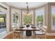 Sun-drenched dining area with a wood table, white chairs, and large windows overlooking the outdoor view at 968 Woodtrace Ln, Auburn, GA 30011