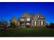 Elegant brick home with a manicured lawn and subtle landscape lighting under a beautiful twilight sky at 968 Woodtrace Ln, Auburn, GA 30011
