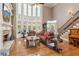 Grand living room with hardwood floors, a fireplace, floor-to-ceiling windows, and a staircase at 968 Woodtrace Ln, Auburn, GA 30011